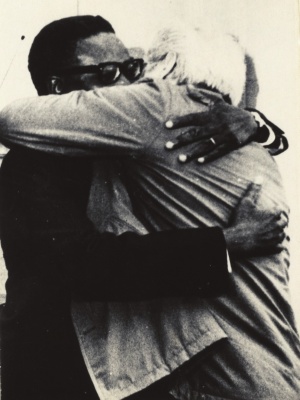 Agostinho Neto em visita ao Centro de Trabalho do PCP (Av. António Serpa, Lisboa) em Janeiro de 1975. O abraço estreito com Álvaro Cunhal simboliza os anos de luta dos dois partidos e os fraternos laços de amizade que sempre os uniram. A própria evasão de Portugal de Agostinho Neto, em 6 de Julho de 1962, foi realizada com o apoio e envolvimento directo da Direcção do PCP. Agostinho Neto foi o primeiro Presidente da República Popular de Angola; faleceu em 10 de Setembro de 1979